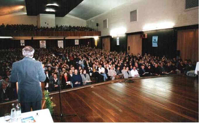 Palestrante no palco diante de um auditório lotado, em evento da ARH Serrana